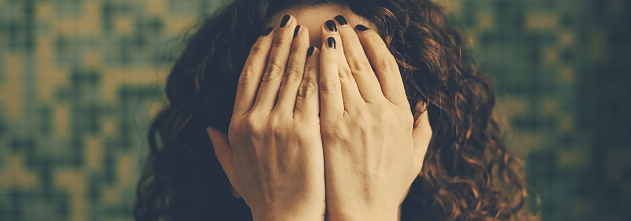 woman holding hands in front of face