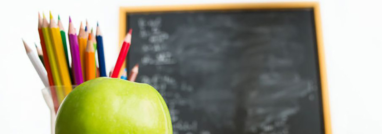 apple and pencils with blackboard in background